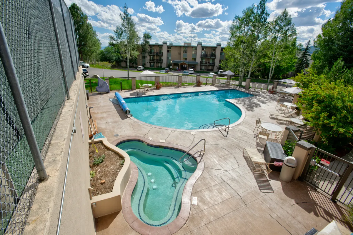 An inviting outdoor spa area with a swimming pool surrounded by greenery, offering a perfect setting for socializing, relaxing, and enjoying the mountain air together.