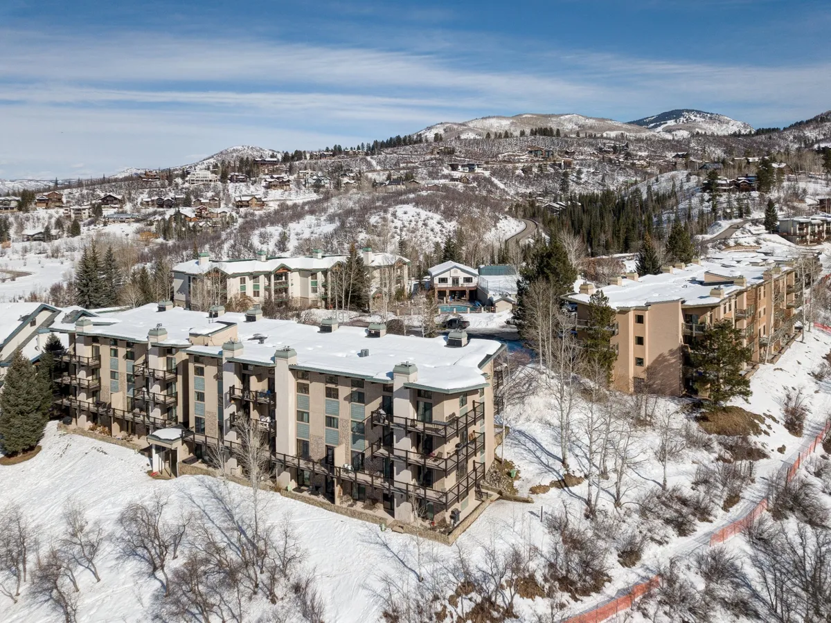 A scenic view of the multi-story building surrounded by a pristine, snow-covered landscape, with distant mountains rising in the background. This image captures the serene winter atmosphere and the property's proximity to nature.