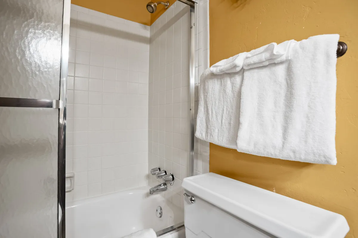 A calming bathroom scene featuring a large bathtub and separate shower area, with fresh white towels and a serene, spa-like feel. The space is inviting for relaxation and personal wellness moments.