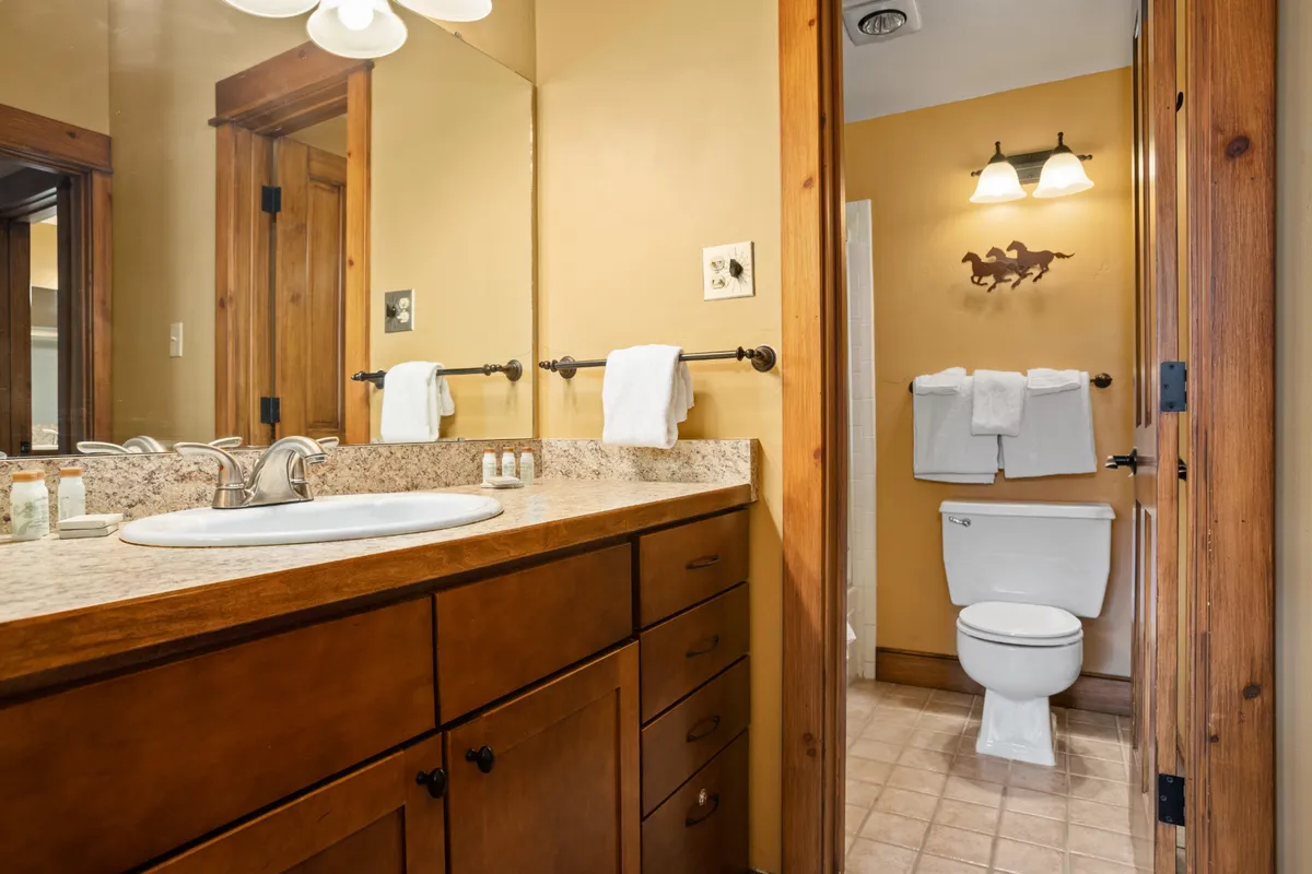 A bathroom with a vanity featuring a sink, wood cabinetry, bath towels, and decorative wall art. The clean, serene design is ideal for personal grooming and relaxation.